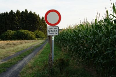 Road sign on field against sky