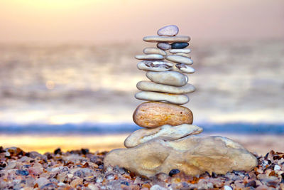 Stack of pebbles on beach against sky during sunset