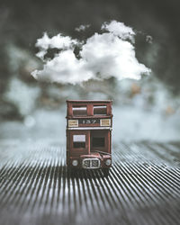 Digital composite image of toy car against clouds