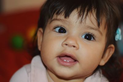 Close-up of cute baby girl looking away at home