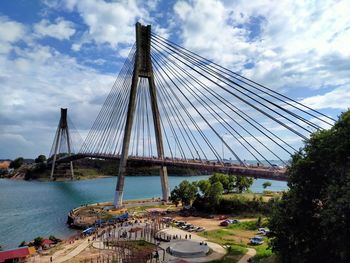 Suspension bridge over river against sky