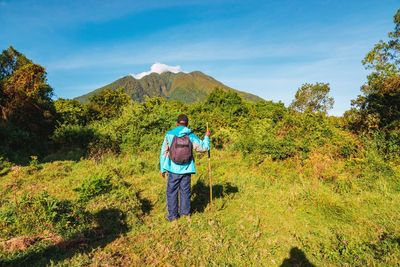 Rear view of a hiker against mount sabyinyo in the mgahinga gorilla national park, virungas, uganda