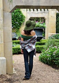 Rear view of young woman wearing hat standing on footpath in park