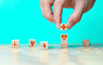 Midsection of hand holding toy against blue background