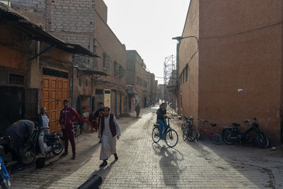 People riding bicycle on street amidst buildings in city