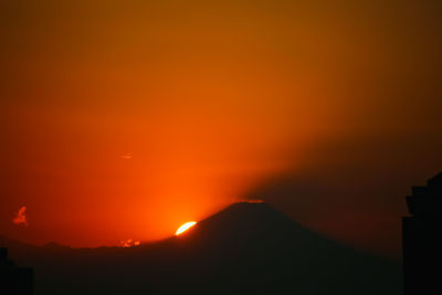 Scenic view of silhouette mountain against orange sky