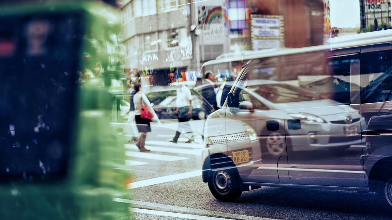 land vehicle, transportation, street, mode of transport, city, car, road, building exterior, built structure, architecture, city street, city life, on the move, full length, casual clothing, outdoors, day, vehicle, busy, rush hour