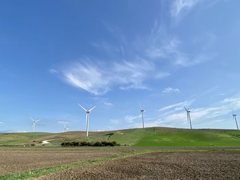 Windmills on field against sky