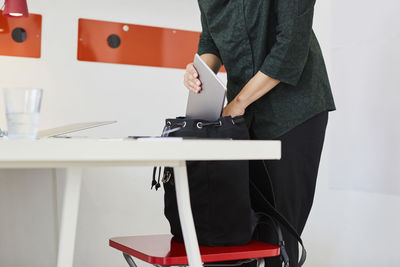 Midsection of businesswoman keeping laptop in bag at office