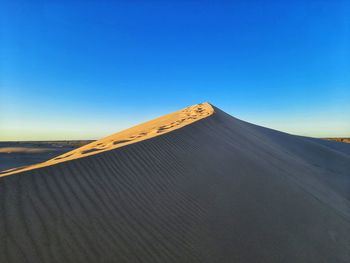 Scenic view of arid landscape against clear blue sky