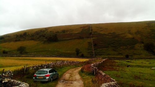 Vehicles on road by mountain against sky