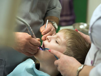 Midsection of dentist examining boy at hospital