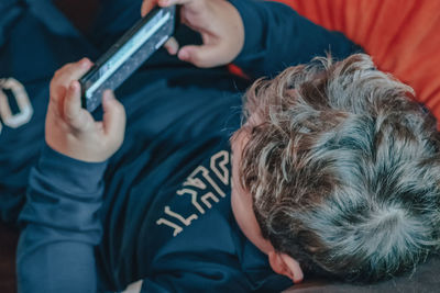 High angle view of a boy playing with mobile phone at home