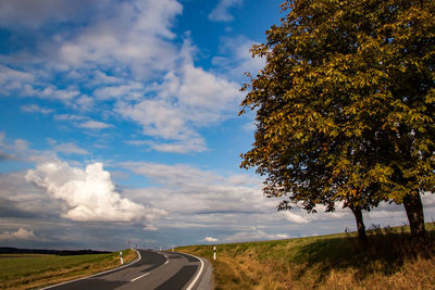 Country road amidst landscape against sky