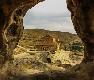 Church against cloudy sky seen through rock 