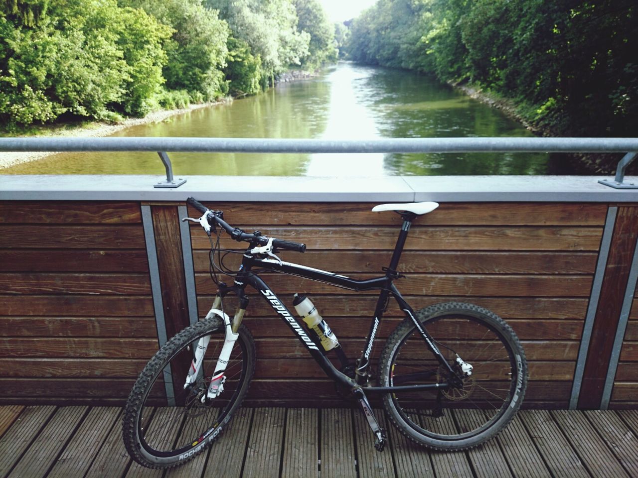 water, railing, transportation, bicycle, mode of transport, tree, river, lake, canal, day, high angle view, reflection, outdoors, metal, nature, no people, nautical vessel, footbridge, tranquility, the way forward