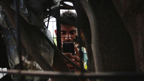 Close-up of man photographing seen through fence