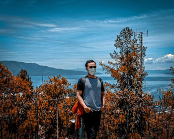 Man standing by tree against sky