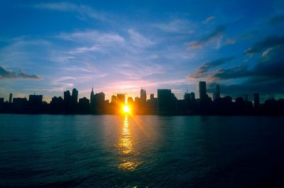 Silhouette buildings by city against sky during sunset in manhattan - new york city