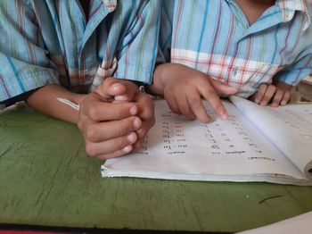 Midsection of man reading book on table