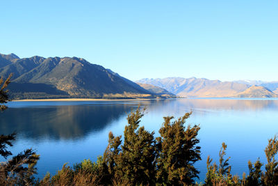 Scenic view of lake and mountains against clear blue sky