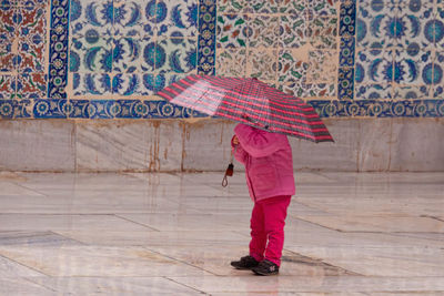 Girl holding umbrella while standing outdoors