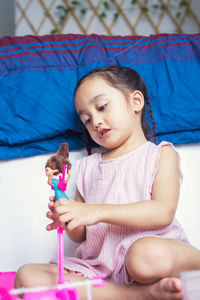 Cute girl playing with doll at home