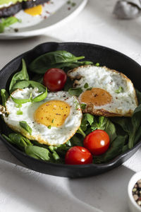 Breakfast with fried eggs and vegetables in a pan