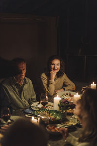 Senior man and woman sitting at dining table during candlelight dinner party