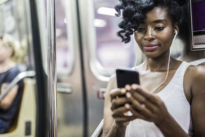 Portrait of woman looking at cell phone in underground train