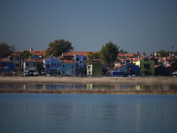 River by houses and buildings against clear sky