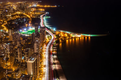 Aerial view of illuminated city by river at night