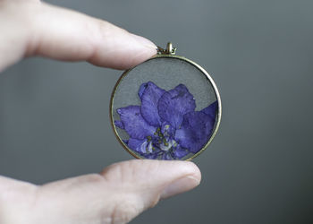 Close-up of hand holding purple against white background