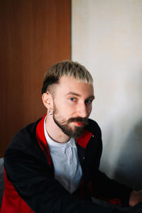 Portrait of young man standing against wall