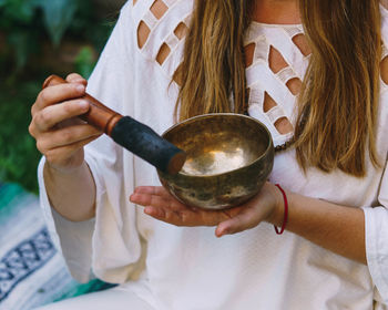 Midsection of young woman holding mortar and pastel while meditating sitting outdoors