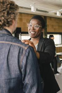 Smiling businesswoman with hand on colleague's shoulder at office