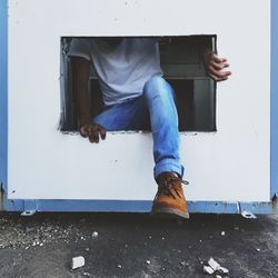 Low section of man stepping out of window