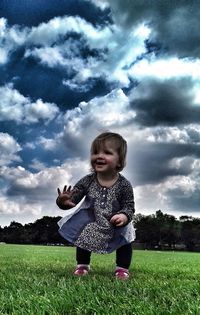 Happy girl playing on field against sky