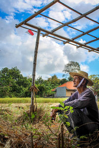 People by plants on landscape against sky