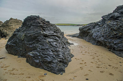 Rock formation on beach against sky