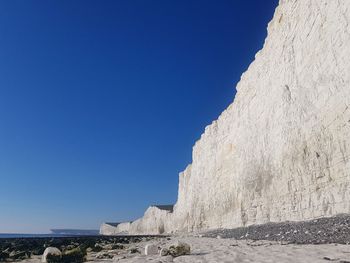 Low angle view of rocks against clear blue sky