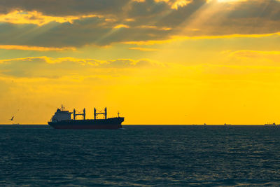 Ship sailing on sea against sky during sunset