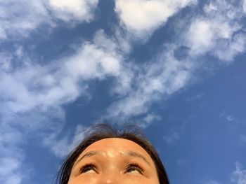 Low angle portrait of woman looking away against sky