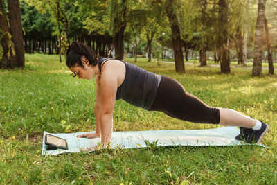  brunette woman plus-size body positive practices sports in nature. woman does yoga in the park