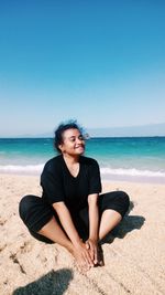 Young woman on beach against clear sky