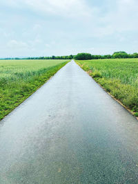 Road amidst field against sky
