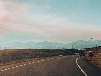 Road leading towards mountains against sky