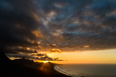 Scenic view of mountains by sea against sky during sunset