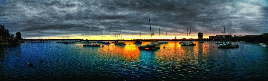 Boats in harbor against cloudy sky