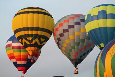 Low angle view of multi colored hot air balloons flying against clear sky